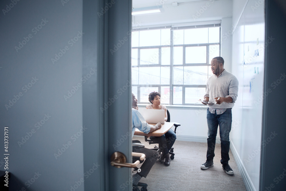 Businessman discussing with colleagues in board room seen through glass door Businessman discussing with colleagues in board room seen through glass door