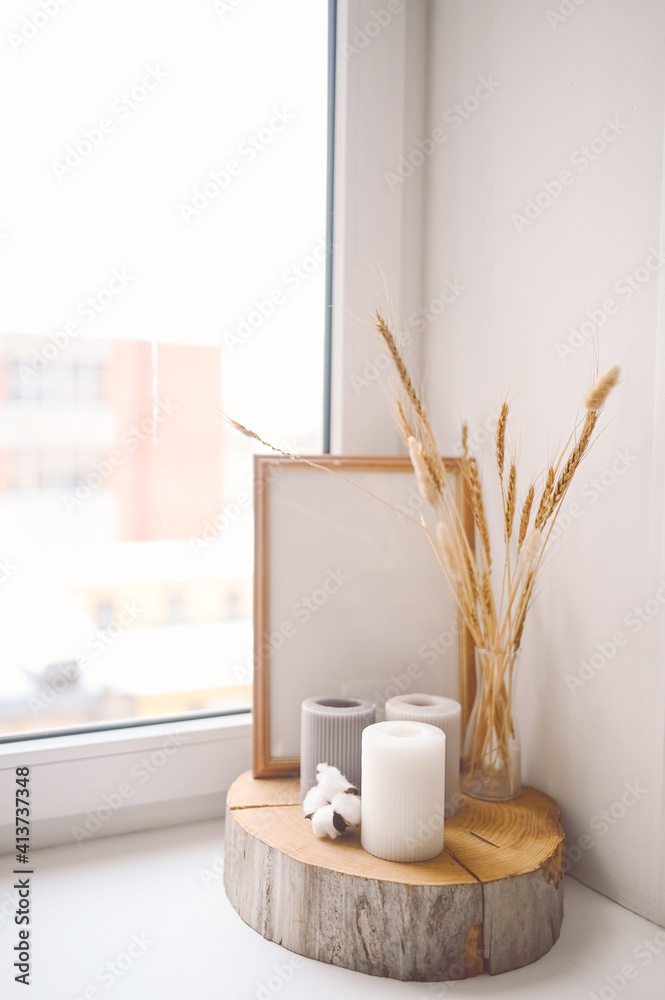 Cozy still life feminine scene pastel colors. Female styled window sill minimalistic composition. Empty mock up poster frame, elegant accessories, candles, dry flowers spikelets.