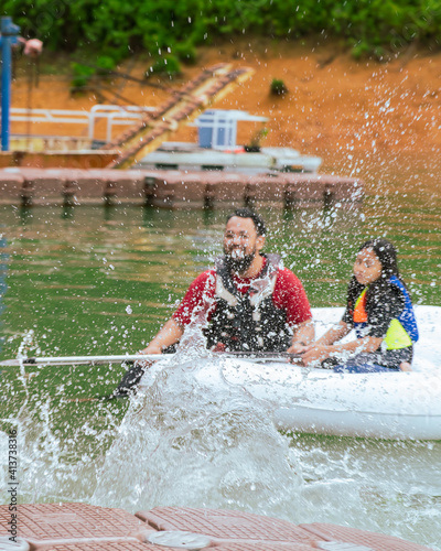 Water splash near family paddling on an inflatable boat at the Lake Kenyir, Malaysia.