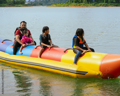 Family enjoying water activities on banana boat at the Kenyir Lake, Terengganu, Malaysia. © ellinnur