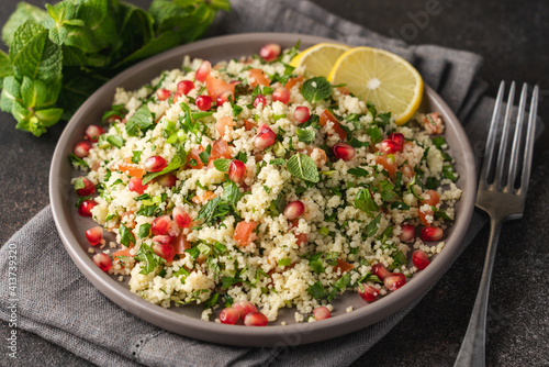 Tabbouleh salad with couscous, tomato, mint, parsley and pomegranate seeds. Traditional Middle Eastern cuisine 