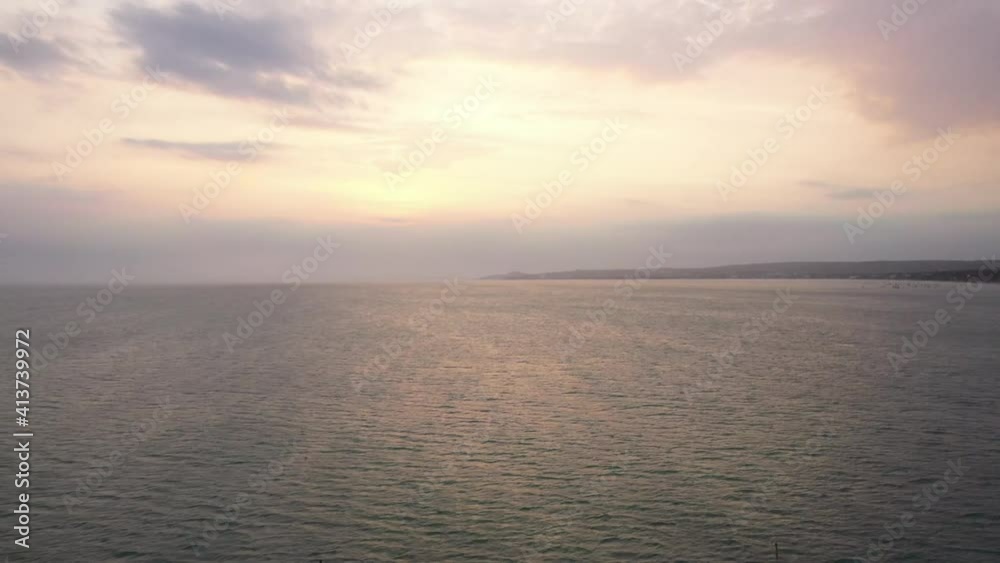 Aerial view to sea and sunset nude sky. Drone flies over water, gentle sunset beige sky and its reflection in the ocean Aerial view to sea and sunset nude sky. Drone flies over water, gentle sunset beige sky and its reflection in the ocean
