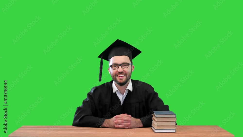 Young graduated man at the desk pointing to the sides presenting something on a Green Screen, Chroma Key. Young graduated man at the desk pointing to the sides presenting something on a Green Screen, Chroma Key.