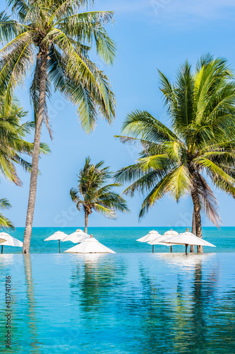 Umbrella and chair around outdoor swimming pool with coconut palm tree