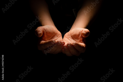 Begging, empty palms, outstretched hands. Concept of social disadvantage, black background.