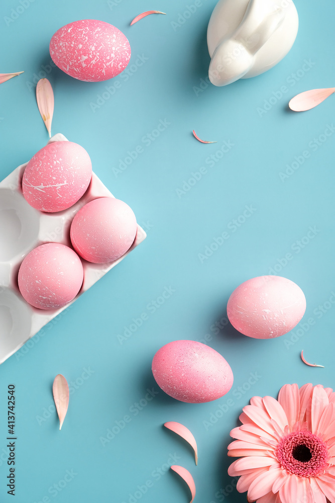 Pink Easter eggs, bunny rabbit, spring flowers on turquoise background. View from above, flat lay. Vertical banner for social media stories.