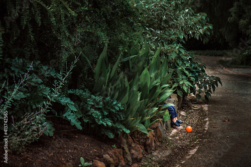 Low section of boy sitting by plants in park