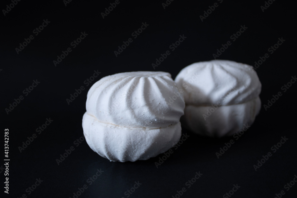 Obraz premium Two vanilla marshmallows on a black background close-up.