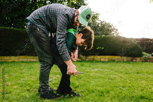 Father assisting son in cutting stick with knife at Newbury Park photo