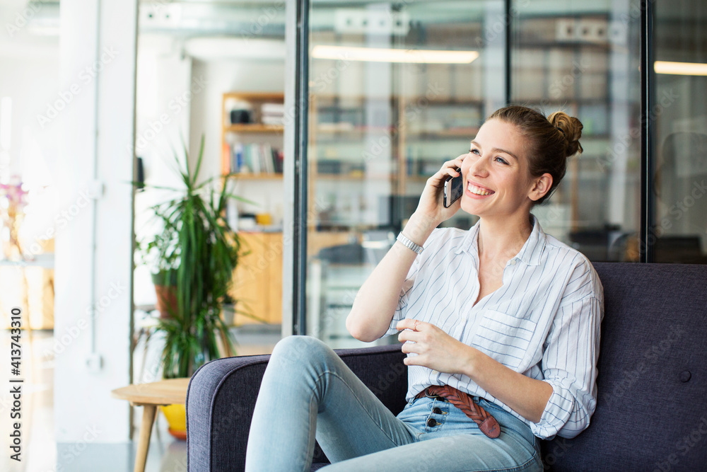 Happy businesswoman talking on mobile phone while sitting at office Happy businesswoman talking on mobile phone while sitting at office