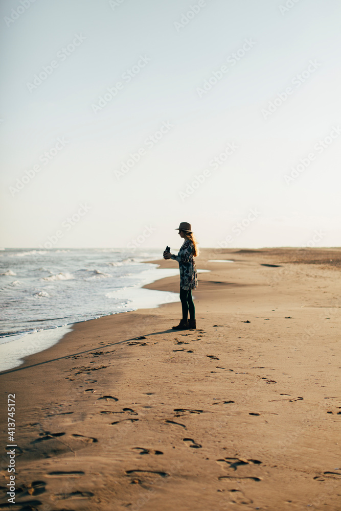 Woman holding camera enjoying at beach against clear sky during sunny day Woman holding camera enjoying at beach against clear sky during sunny day