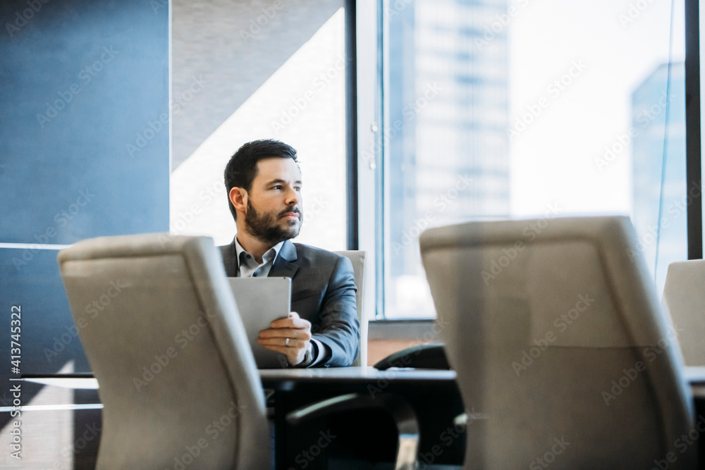 Thoughtful businessman looking away while sitting in board room Thoughtful businessman looking away while sitting in board room