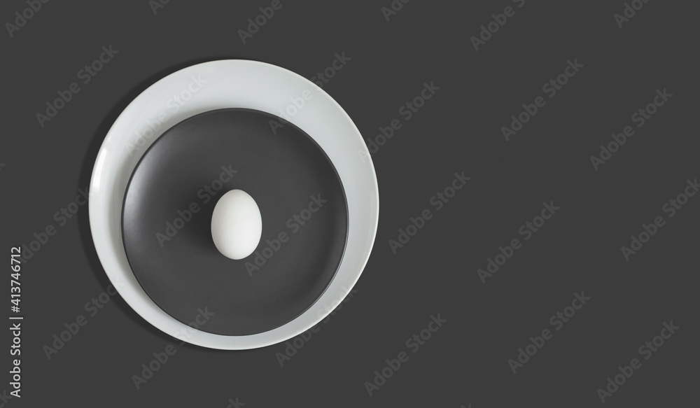 Grey Easter concept. White chicken egg in a gray white plate on a gray background. Abstract minimal gray background. Copy space, top view Grey Easter concept. White chicken egg in a gray white plate on a gray background. Abstract minimal gray background. Copy space, top view