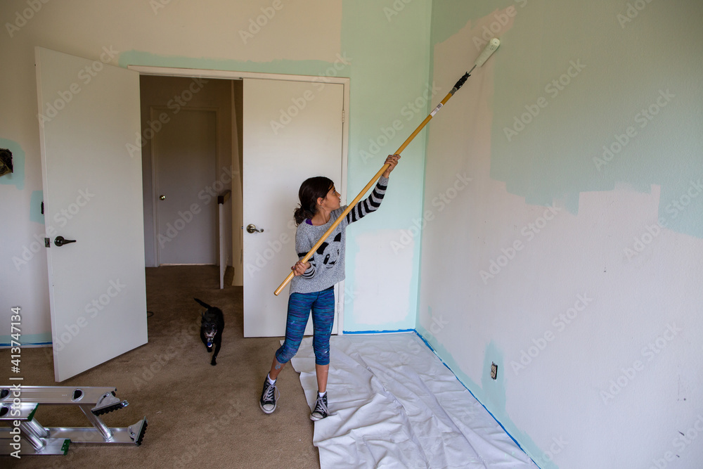Girl painting wall using paint roller at home Girl painting wall using paint roller at home