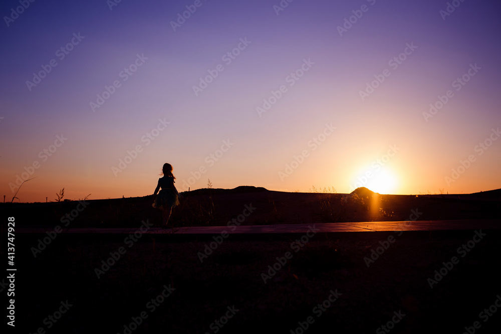 Silhouette girl standing at park against sky during sunset Silhouette girl standing at park against sky during sunset