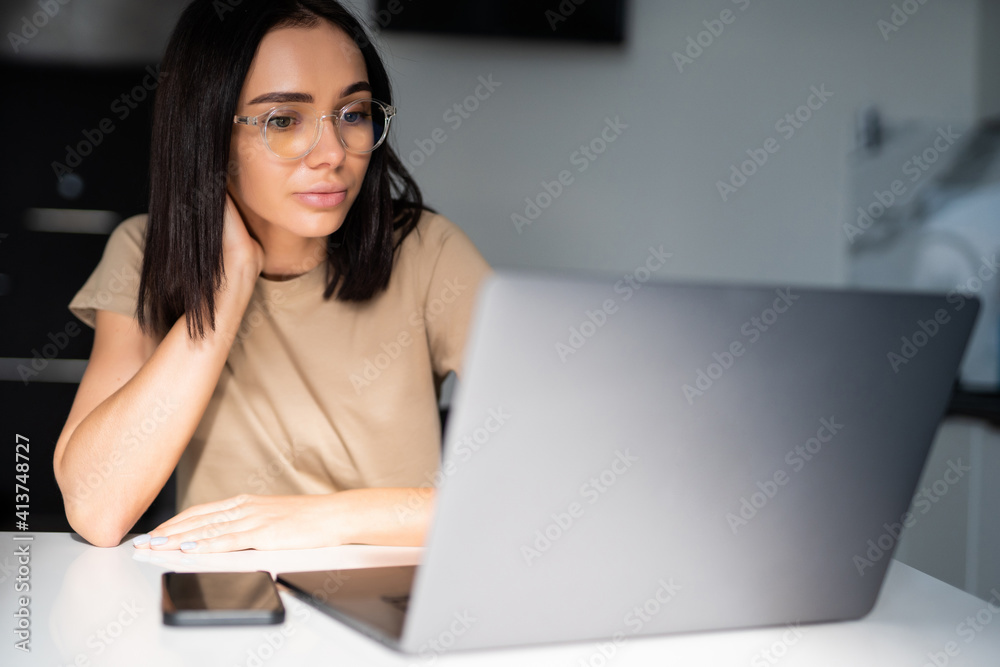 Young woman typing on her laptop in the kitchen Young woman typing on her laptop in the kitchen