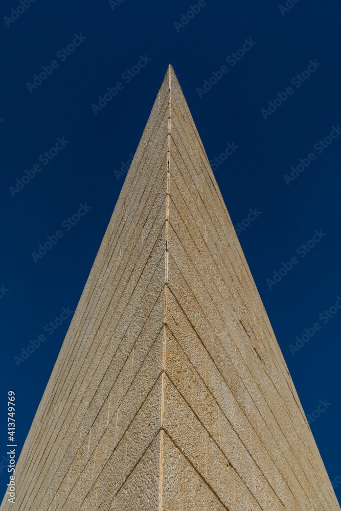 Architectural structure in the form of a pyramid, lined with tiled stone, against a blue sky.Copy space Architectural structure in the form of a pyramid, lined with tiled stone, against a blue sky.Copy space