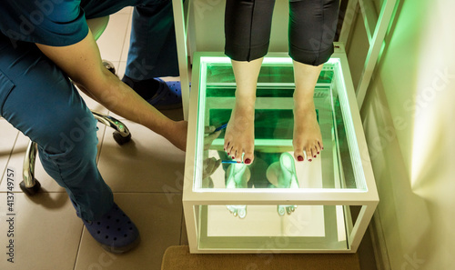 Doctor is at examining womans feet by using plantoscopy device photo