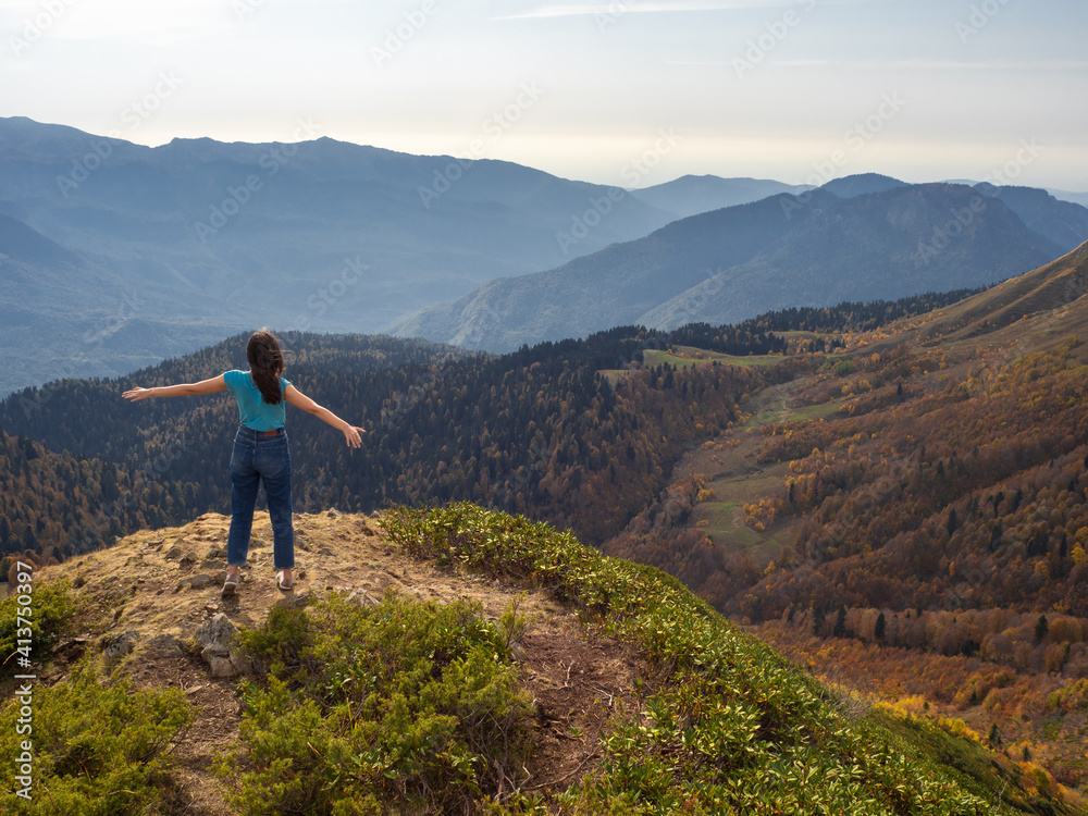 tourist stands on top of a mountain with her arms outstretched, Hiking in the mountains.