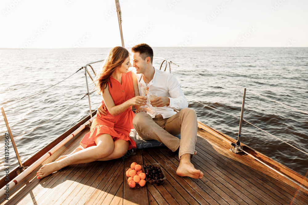 Lovely couple in love on a yacht drinking champagne, luxury rest on the ship.