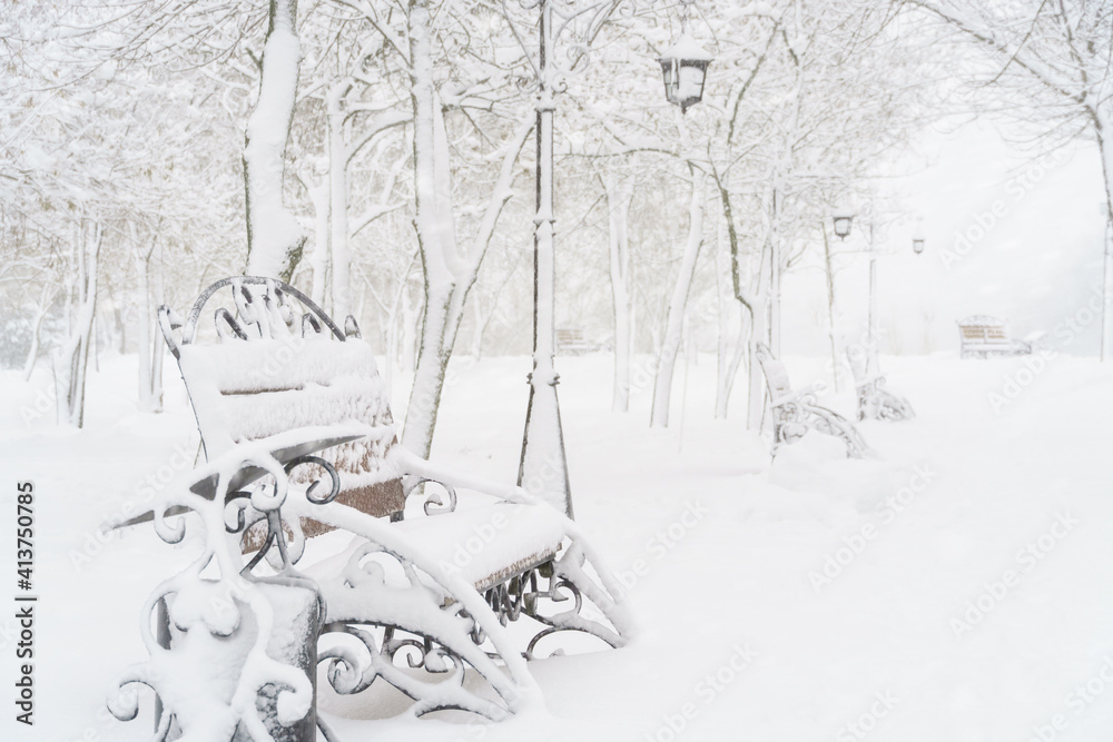 winter city park, benches covered in snow and snowfall winter city park, benches covered in snow and snowfall