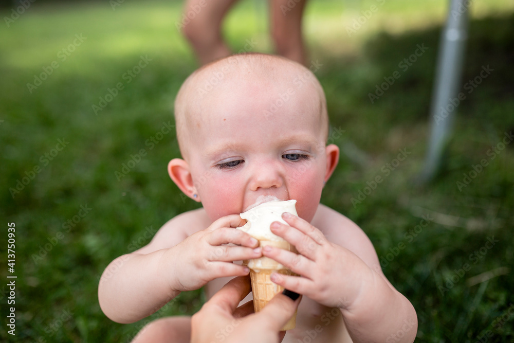 Cropped hand of mother feeding ice cream to daughter in yard Cropped hand of mother feeding ice cream to daughter in yard