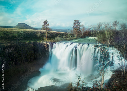 Majestic view of waterfall at White River Falls State Park against sky photo