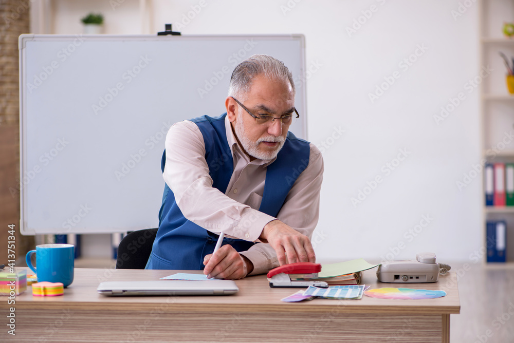 Old male designer working in the office Old male designer working in the office