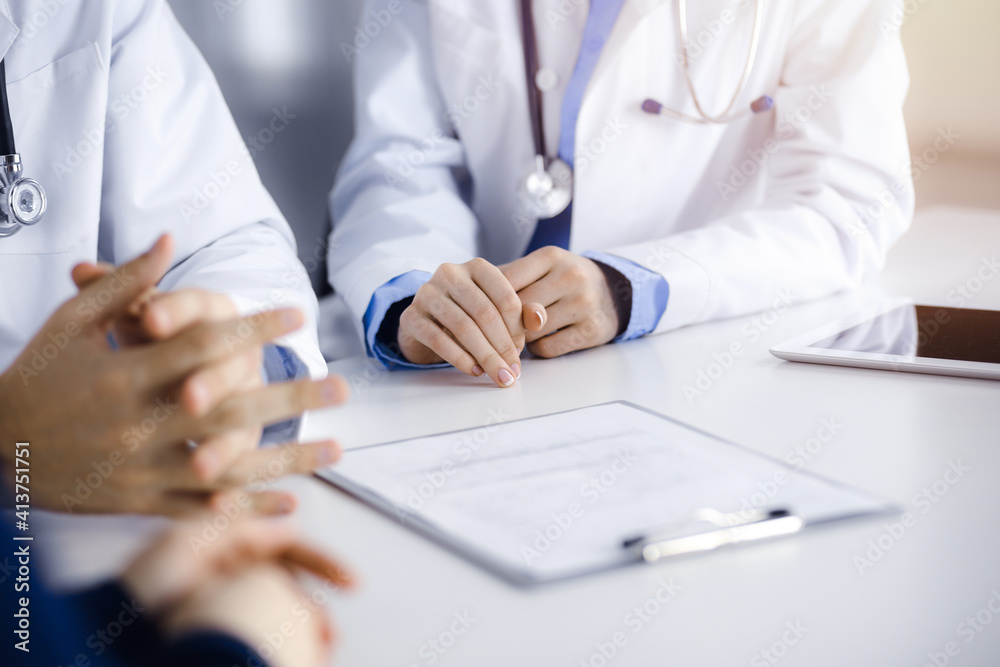 Group of unknown doctors are sitting at the desk and discussing problems or disease treatment in sunny hospital office. Covid 2019 Group of unknown doctors are sitting at the desk and discussing problems or disease treatment in sunny hospital office. Covid 2019
