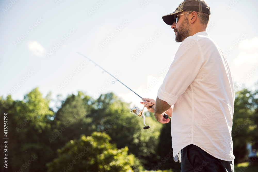 Low angle view of man fishing against trees and sky Low angle view of man fishing against trees and sky