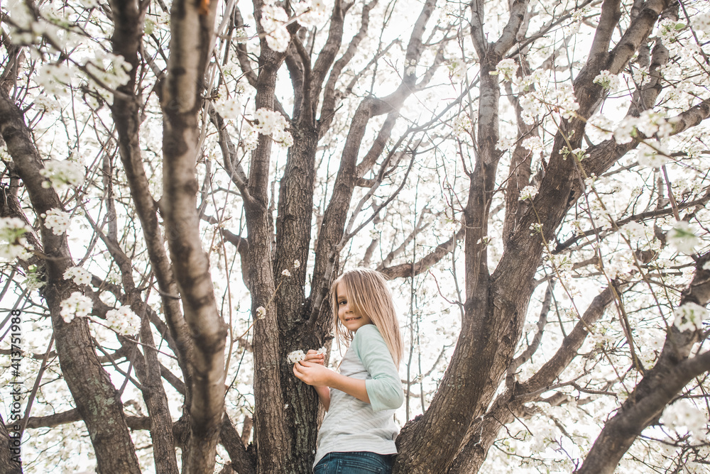 Low angle portrait of girl holding flowers while standing on tree Low angle portrait of girl holding flowers while standing on tree