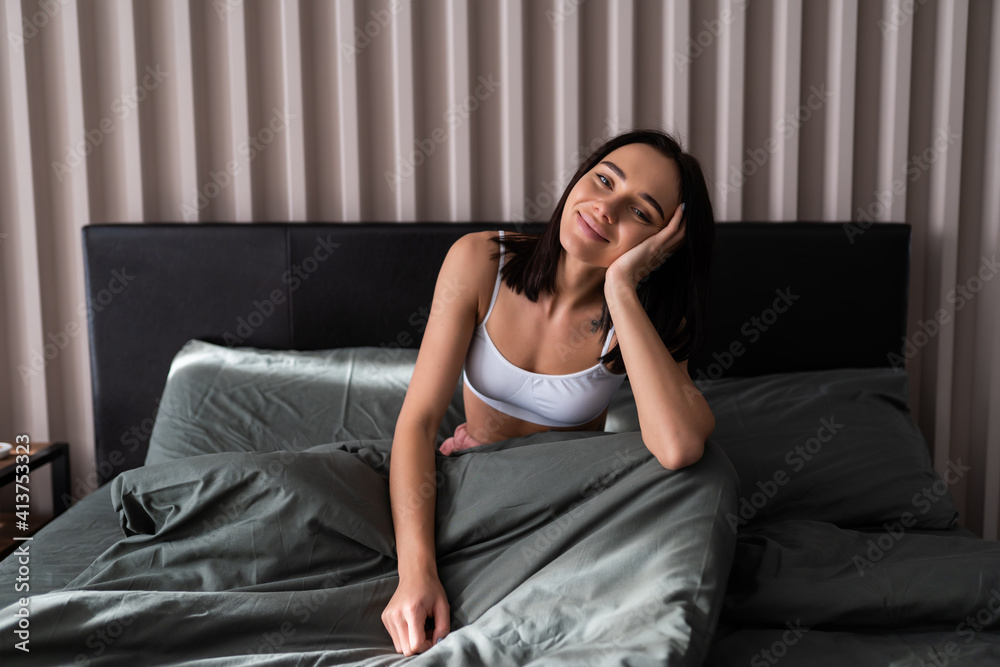 Obraz premium Attractive young woman waking up in bed in the morning