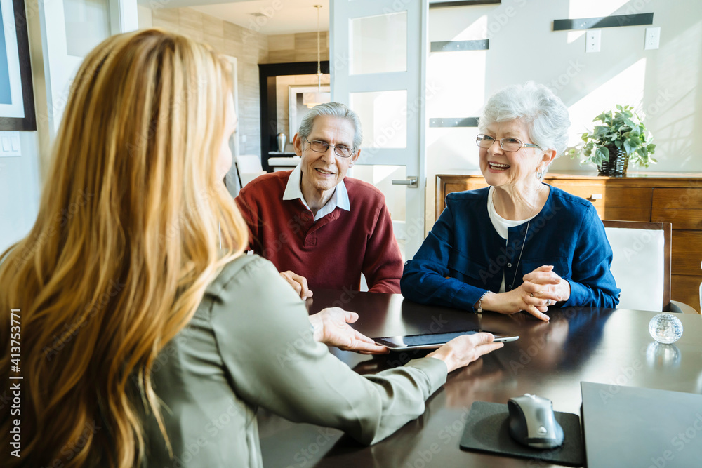 Female financial advisor explaining plan to senior couple on tablet computer in office Female financial advisor explaining plan to senior couple on tablet computer in office