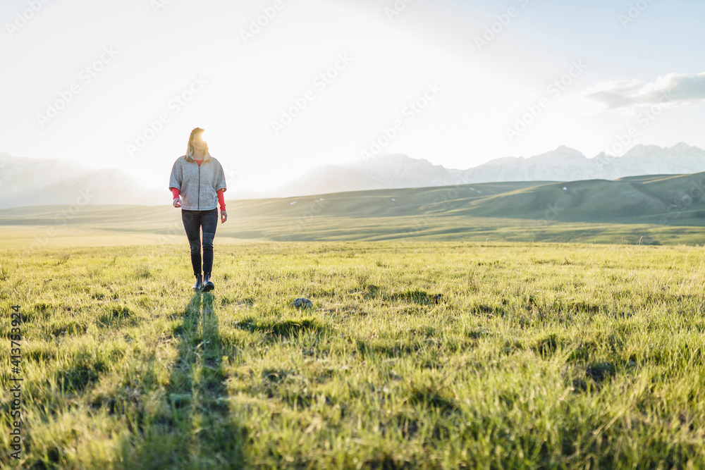 Full length of female hiker walking on grassy field Full length of female hiker walking on grassy field