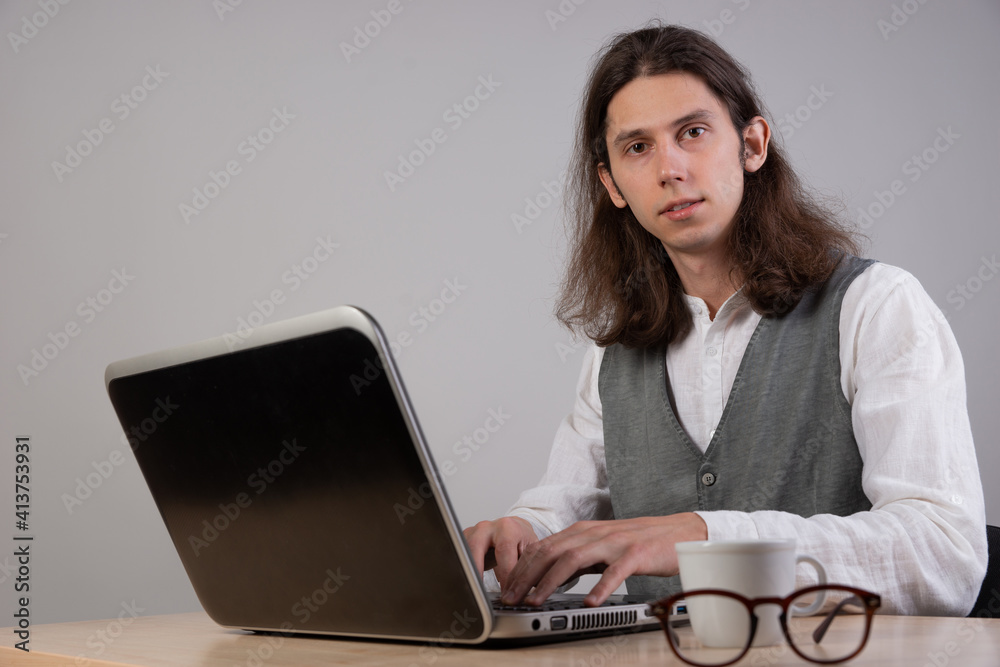 Programming and application development, a young man writes code sitting at a laptop. Programming and application development, a young man writes code sitting at a laptop.