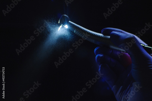 Dentist hand with drill illustrates the operation of the dentist dental drill machine with water