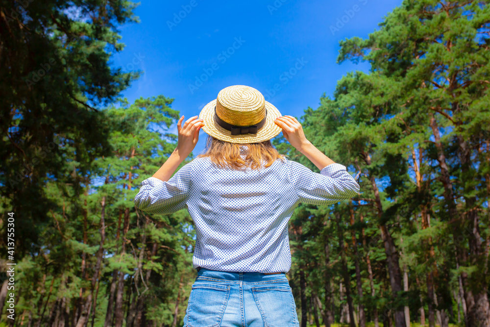 Hipster girl in straw hat standing in the forest. Wanderlust concept. Travelling ideas. Beautiful woman in the nature. Summer vibes.
