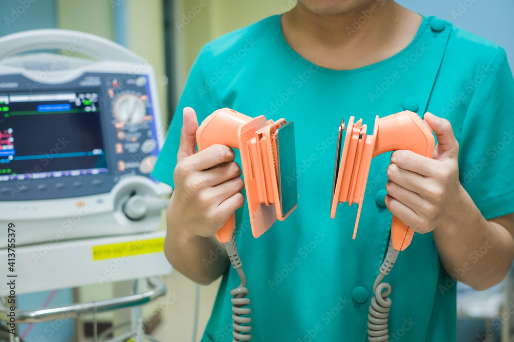 Nurse holding defibrillator, performing defibrillation on a patient