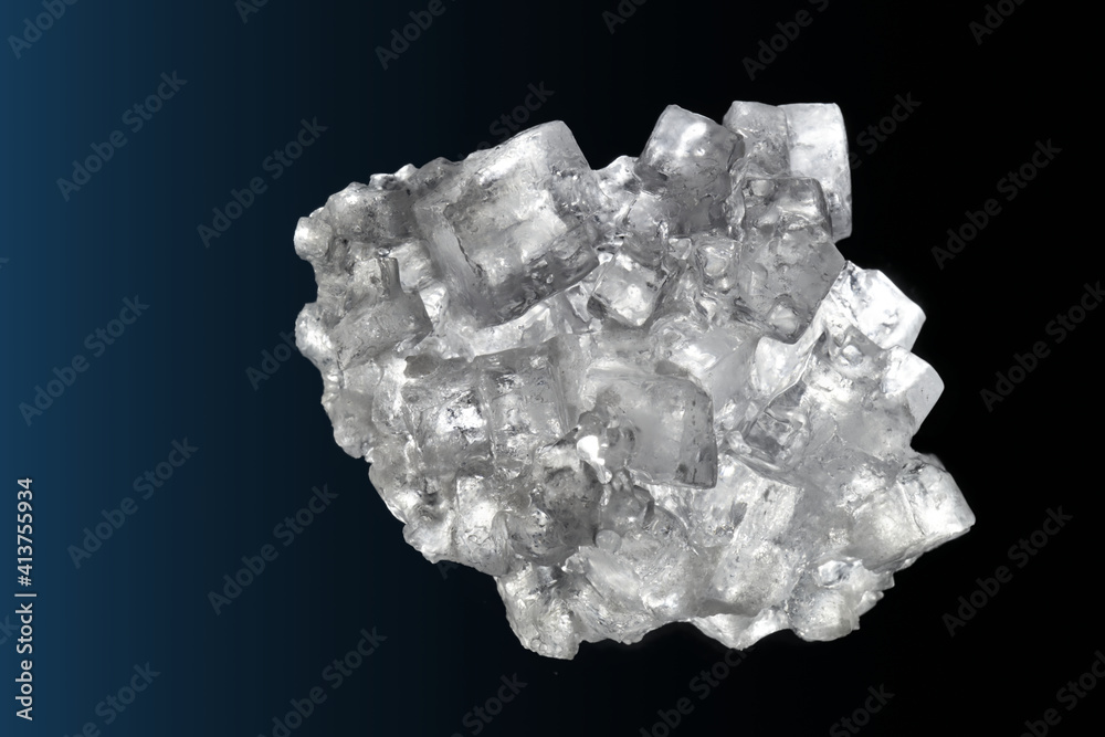 Aggregate of many almost transparent cubic salt crystals in front of a dark background Aggregate of many almost transparent cubic salt crystals in front of a dark background