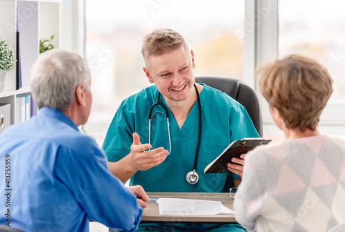 Photography Physician talking to mature couple in cabinet
