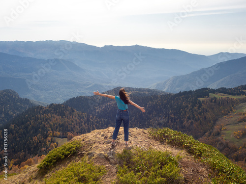 tourist stands on top of a mountain with her arms outstretched, Hiking in the mountains.