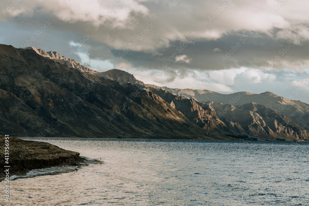 Sun grazes rugged mountains and beach on Lake Hawea, New Zealand Sun grazes rugged mountains and beach on Lake Hawea, New Zealand