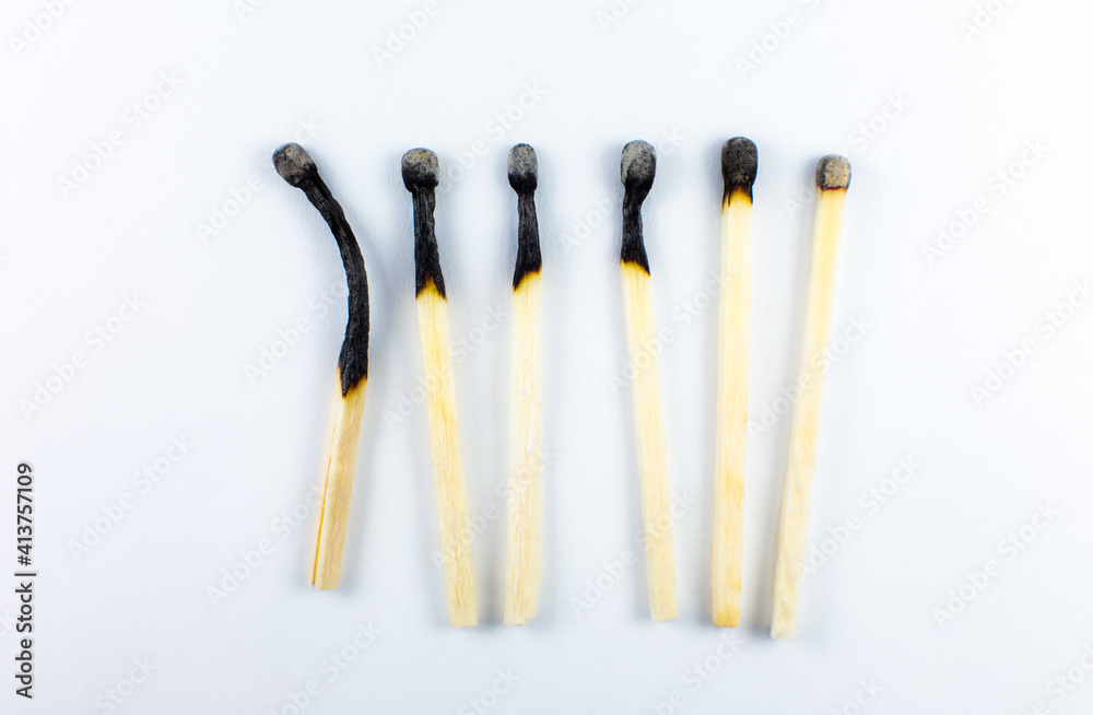 An extinct match in a man's hand. Death and aging concept. Burned matches in a row on a white background. Burnout. An extinct match in a man's hand. Death and aging concept. Burned matches in a row on a white background. Burnout.