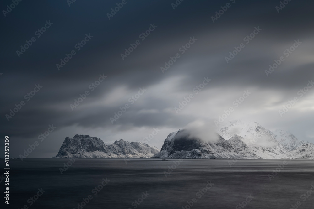 Dramatic light of winter storm clouds sweeping over distant mountains
