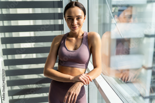 Beautiful fitness young woman while leaning on window at home