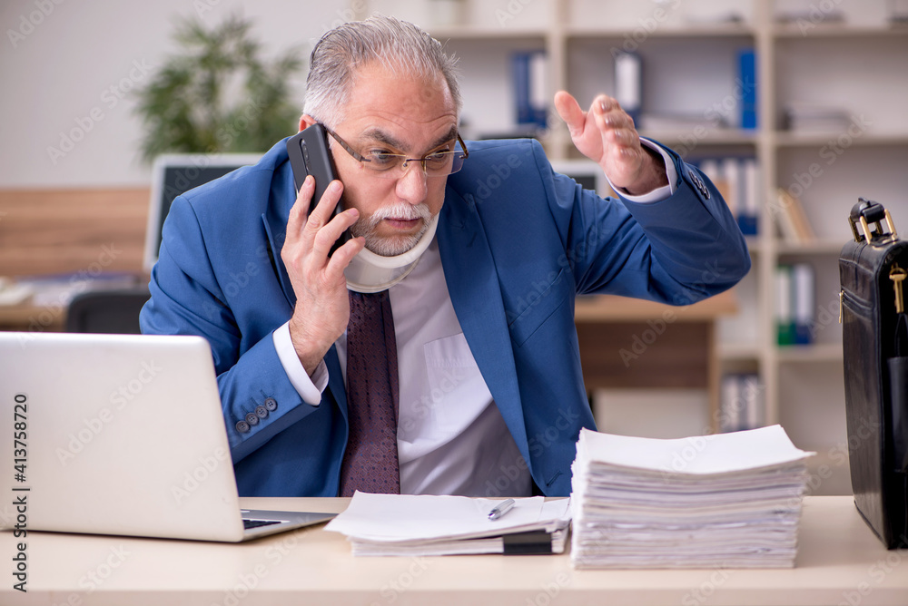 Old businessman employee after accident working in the office Old businessman employee after accident working in the office
