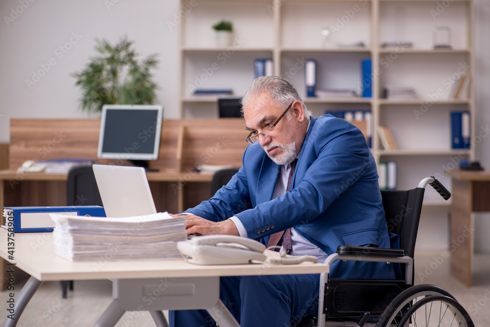 Old businessman employee in wheel-chair working in the office Old businessman employee in wheel-chair working in the office