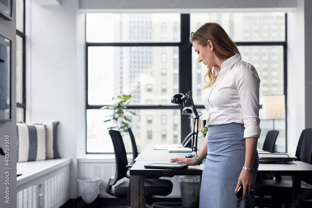 Businesswoman using tablet computer on desk while standing in office Businesswoman using tablet computer on desk while standing in office