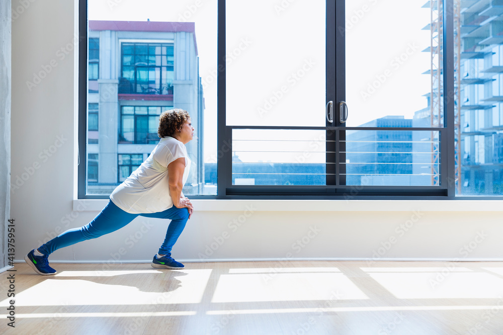Full length of woman stretching legs against window in yoga studio Full length of woman stretching legs against window in yoga studio