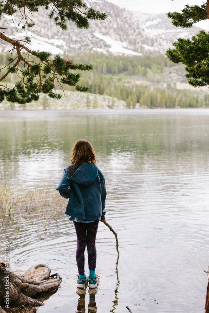 Rear view of girl with stick standing in lake at Inyo National Forest Rear view of girl with stick standing in lake at Inyo National Forest